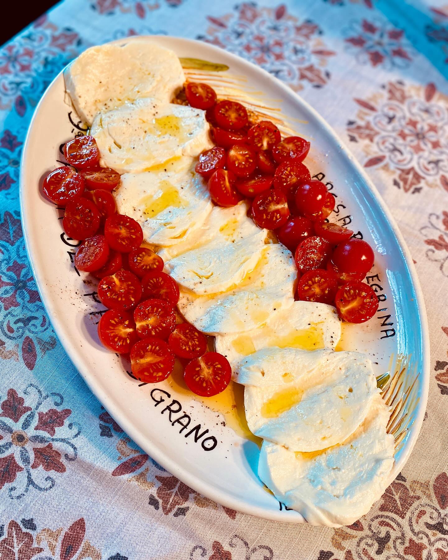 Sliced whole milk Mozzarella with a few cherry tomatoes 🍅- lots of bread off camera.